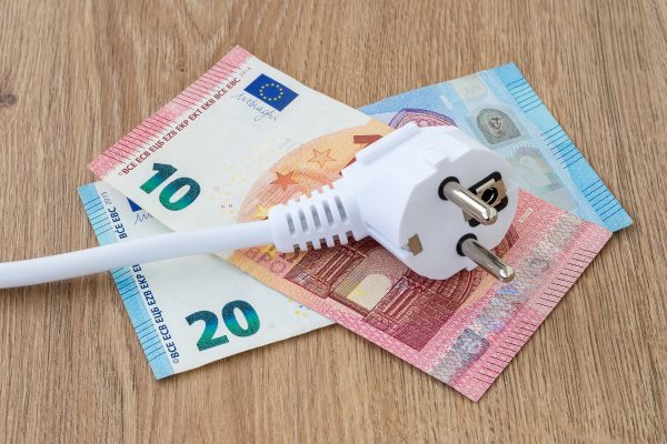 White Power Plug On Euro Banknotes Over A Brown Wooden Surface. Cost Of Electricity And Expensive Energy Concepts.