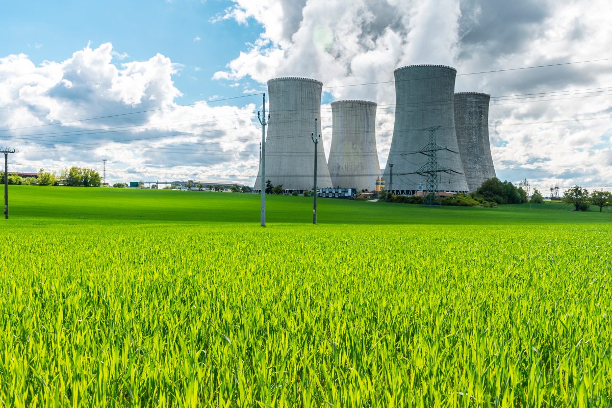 Cooling Tower Of Nuclear Power Plant Behind Green Grass. Atomic Energy. Nuclear Power And The Environment.